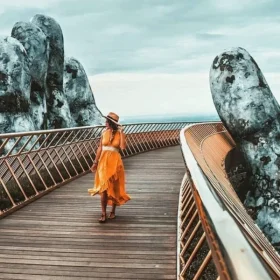 Visitors taking photos on the Golden Bridge Ba Na, with the giant hands and surrounding mountains, showcasing the beautiful landscape.