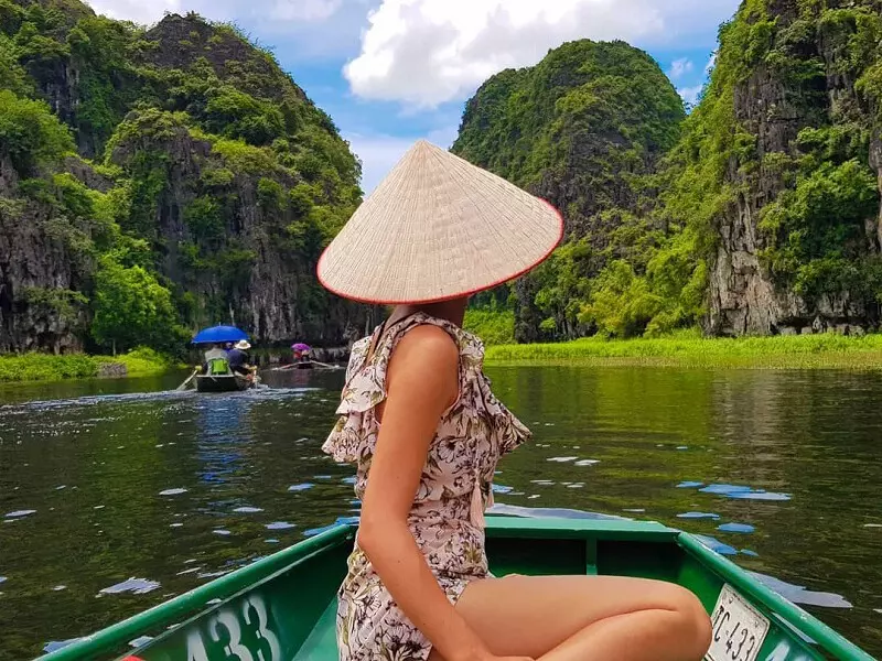 Tam Coc Bich Dong Travel Guide 2025: Top Things to Do, How to Get There & Insider Tips Tourist boat gliding through Tam Coc river surrounded by rice paddies and limestone mountains
