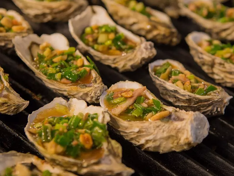 How to Explore Lap An Lagoon in Hue: Full Travel Tips & Guide Close-up of grilled oysters with scallion oil and cheese at a seafood restaurant in Lap An Lagoon, Hue.